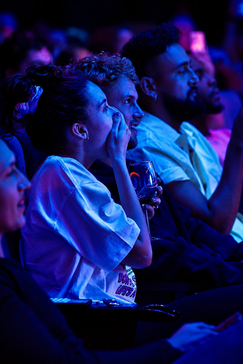 An audience member with her hand over her mouth, laughing in disbelief during the show