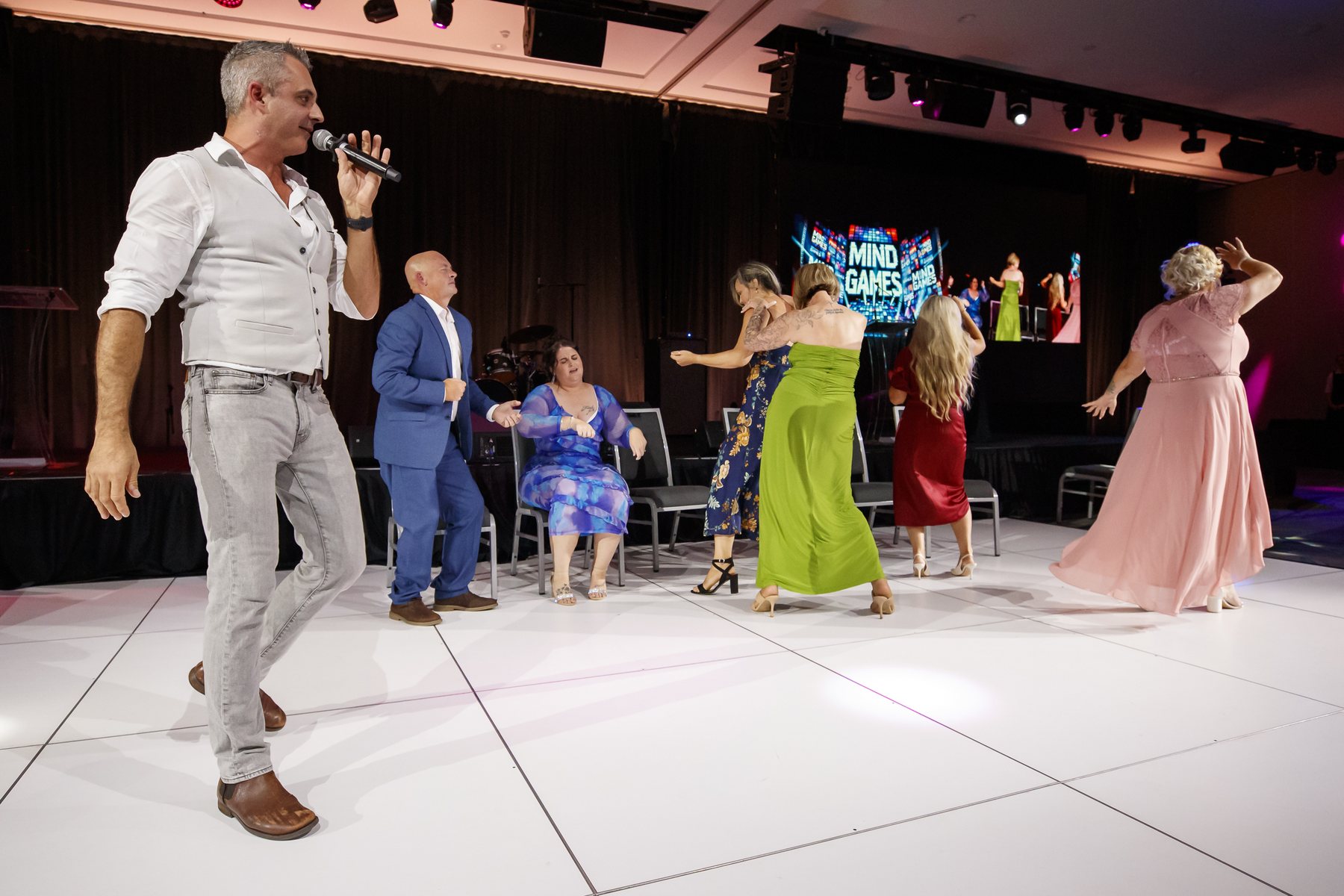 Phoenix running the comedy hypnosis show for volunteers at a corporate function on a white dance floor
