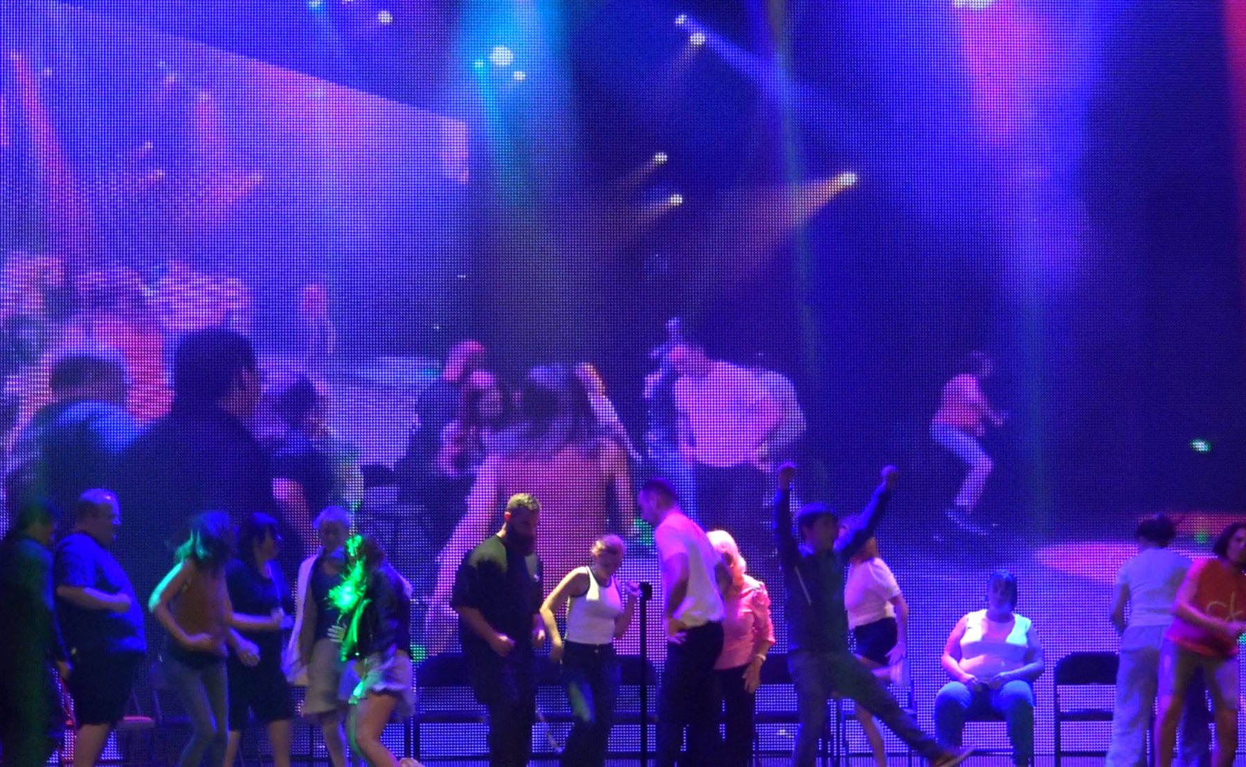 Hypnotised volunteers dancing under coloured lights at the end of the show